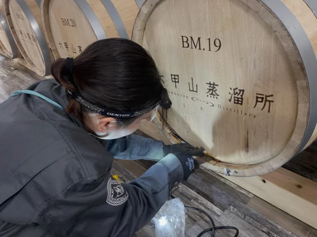 【樽メンテナンス】
今日は、有明産業（国内唯一の洋樽メーカー）さんから、水楢樽のメンテナンスに来て頂きました。女性の職人さんで手際よく🔨補修🪚されていてカッコ良かったです。ミズナラ樽は、名前の通り水分を多く含み木目が粗く多孔質であるため、西洋のホワイトオーク樽に比べてウイスキーが漏れやすい傾向があります。一方で白檀や伽羅のような唯一無二のオリエンタルな香りをウイスキーにもたらします。又長期熟成により比類なき熟成感を生み出してくれます。今回来て頂いた有明産業さんは、希少価値の高い🪵香りを引き出す為高い技術を持ち丁寧な製樽を行っているそうです👏六甲山蒸溜所の水楢ウイスキー🥃を是非お楽しみ下さい⛰️